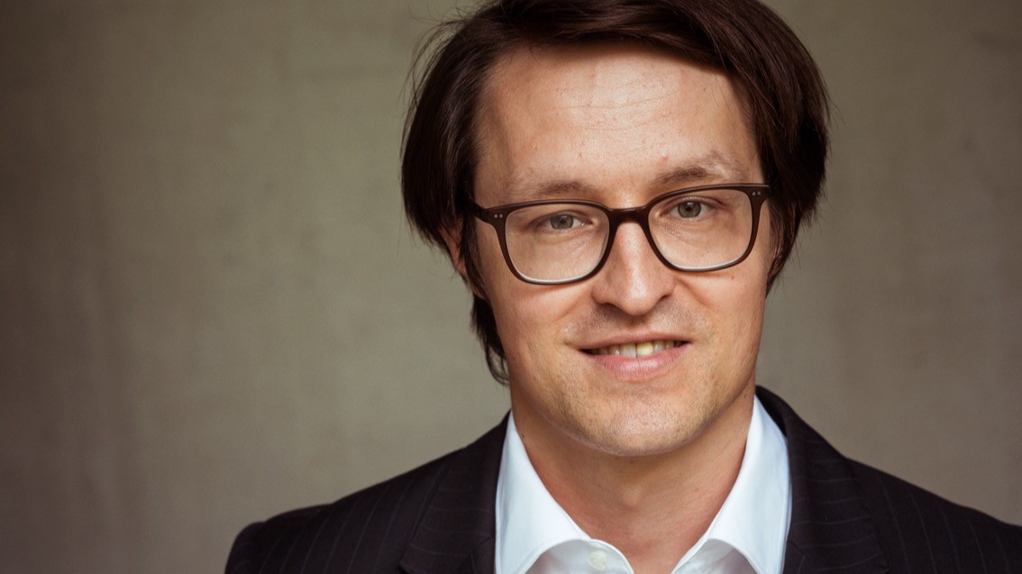 mehrAchtung Cannabis Interview Gutwinski Suchtmediziner Dr. Stefan Gutwinski trägt ein weißes Hemd, ein schwarzes Jackett, eine Brille und lächelt in die Kamera.