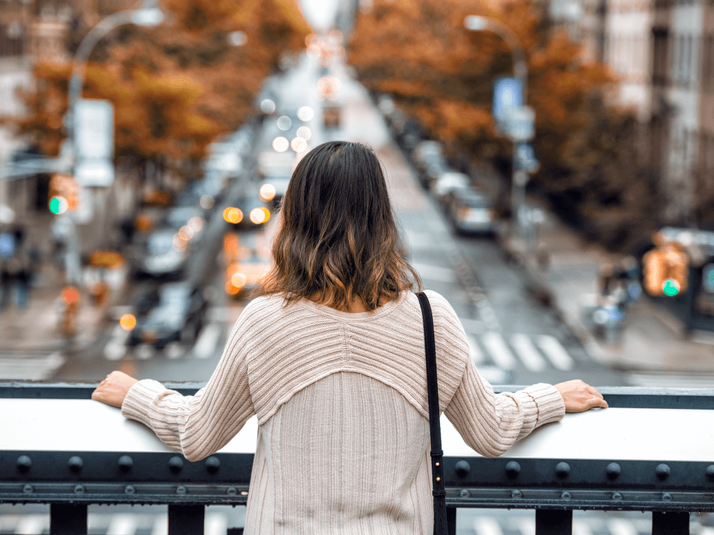 machtderfreundlichkeit Eine Frau sieht von einer Brücke herab auf den Straßenverkehr. Sie wirkt dabei gelassen.