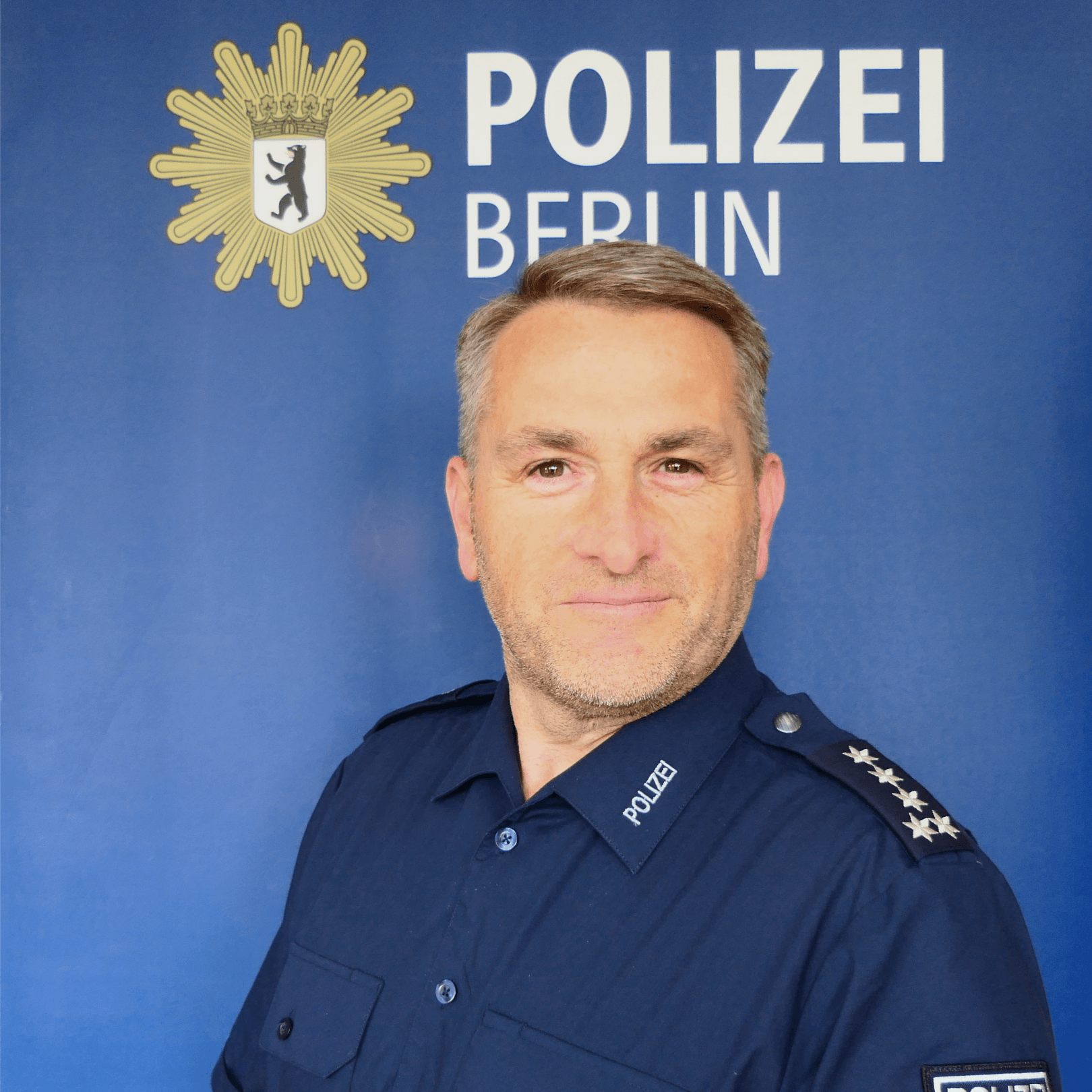 EM Polizist Ein Mann in blauer Uniform lächelt in die Kamera. Er ist Oliver Woitzik von der Berliner Polizei.