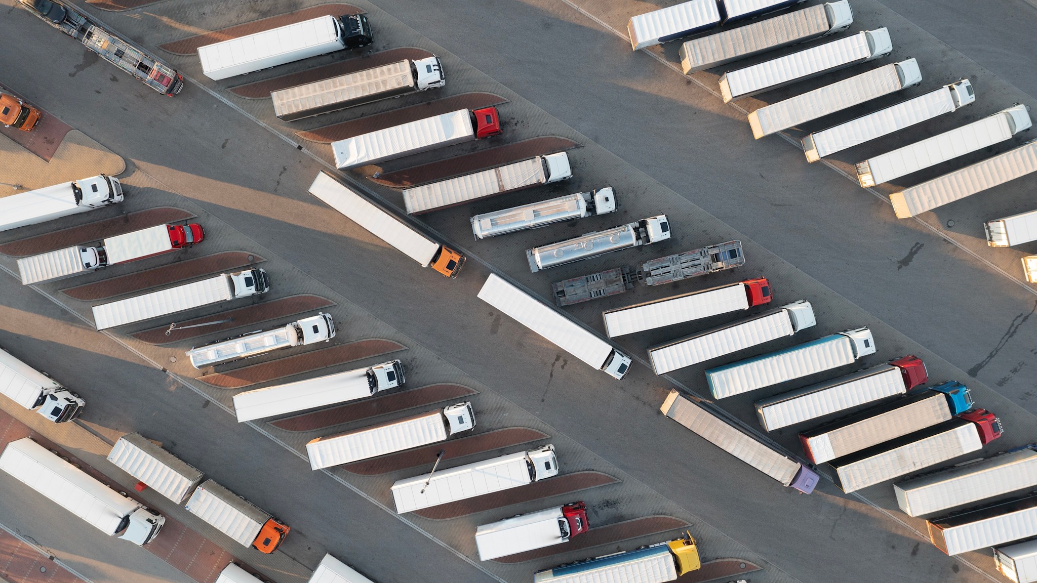 Luftaufnahme eines Autobahnparkplatzes mit vielen abgestellten Lkw.
