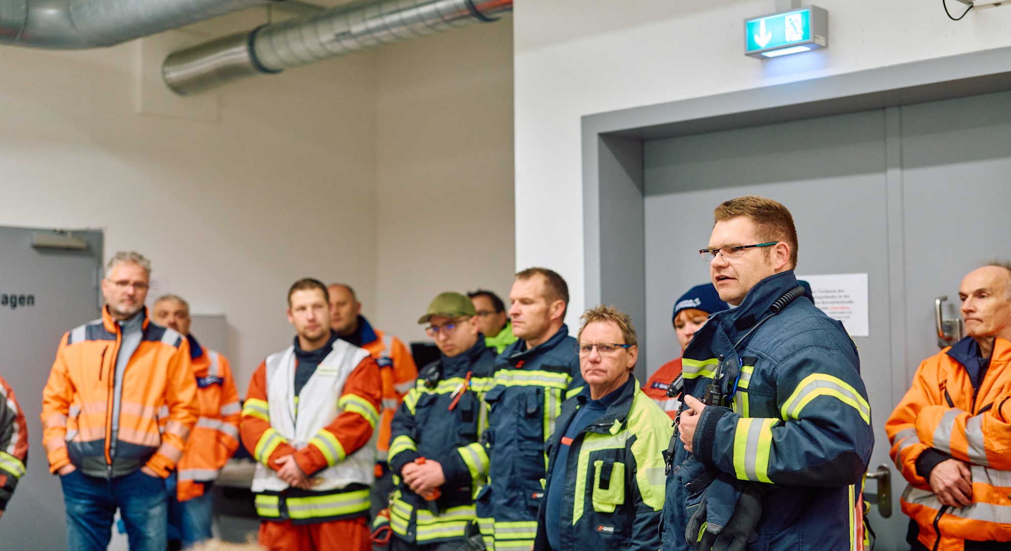 Nach dem Brandtest: Einsatzkräfte und Verantwortliche besprechen den Übungsablauf. In dieser Abschlussbesprechung sammeln sie wichtige Erkenntnisse, um Abläufe weiter zu verbessern und die Sicherheit zu erhöhen.