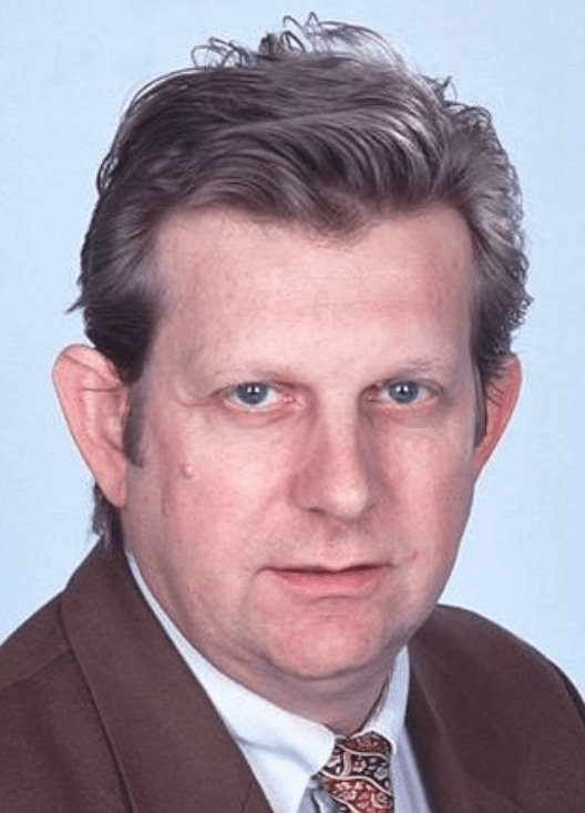 mA Erste Hilfe Porträt Roland Huf Das Porträt zeigt einen Mann, der einen braunen Anzug und eine gemusterte Krawatte trägt. Es ist Roland Huf.