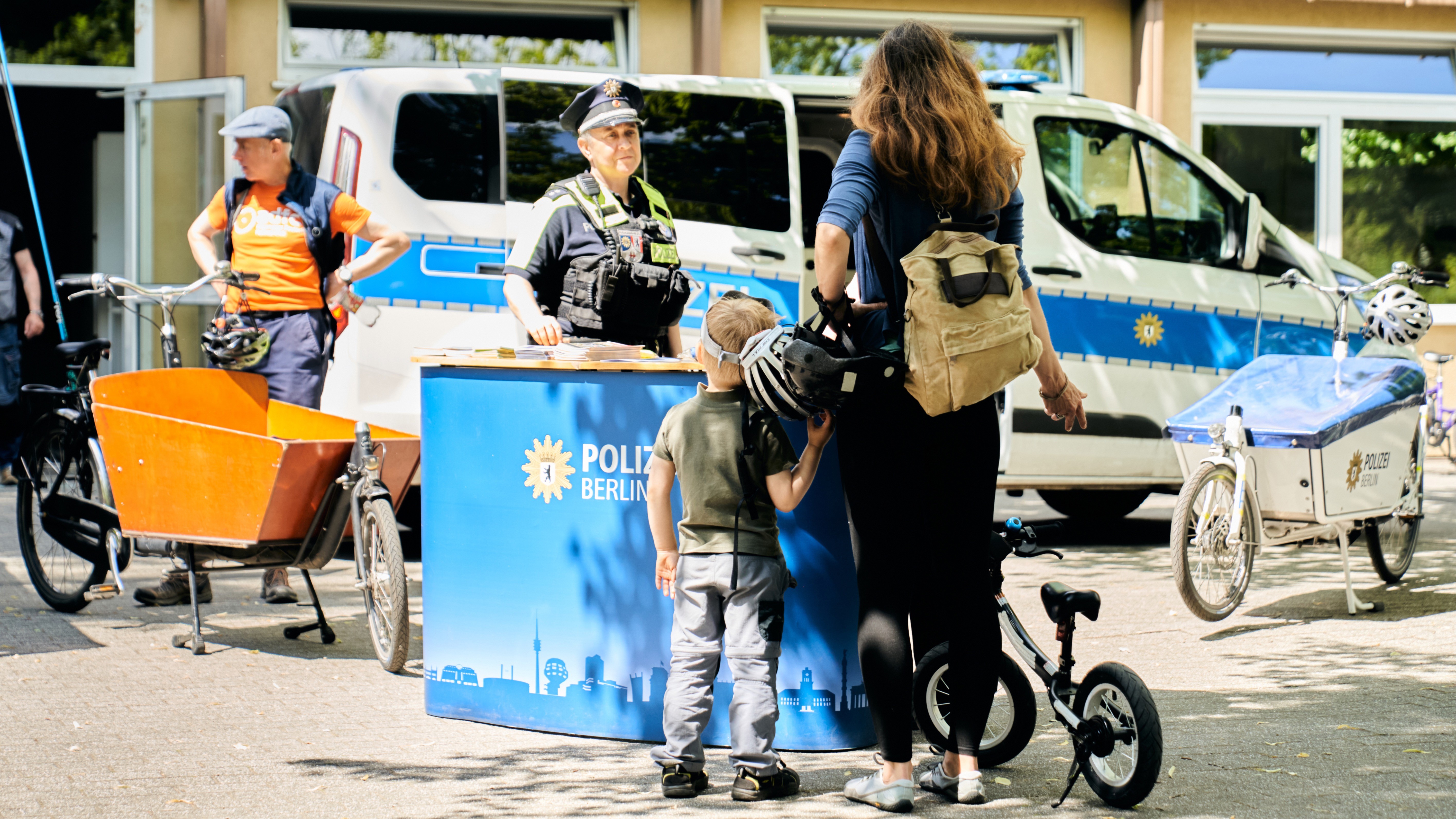 Eine Polizistin informiert Mutter und Kind beim Aktionstag sicher.mobil.leben in Berlin über sichere Schulwege und Kindersicherheit im Verkehr.