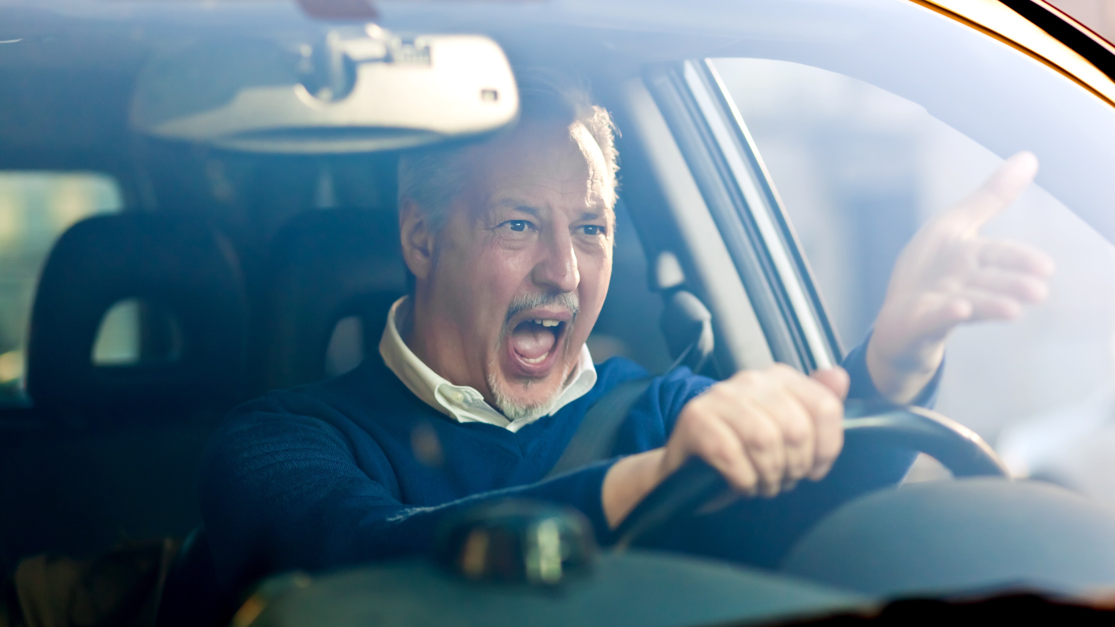 Ein Autofahrer ärgert sich hinter seinem Lenkrad.