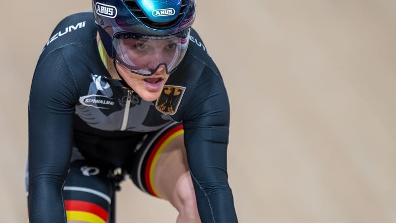 Maike Hausberger Header Eine Bahnradsportlerin fährt Rennrad und trägt Sportkleidung in den Farben Deutschlands sowie einen Helm.