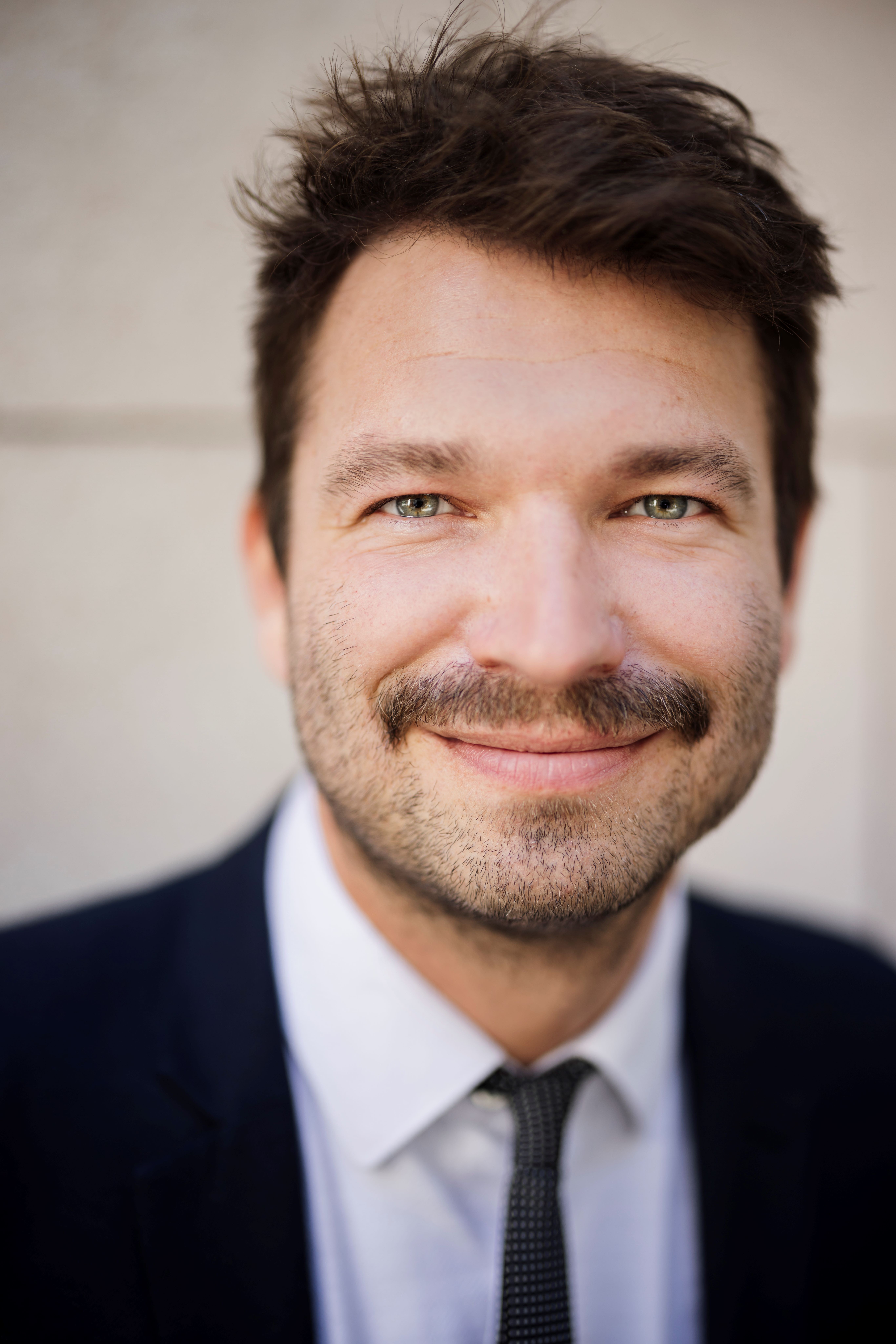 E-Bike oder Pedelec Robin Zalwert Ein Mann in Anzug und Krawatte lächelt in die Kamera. Es ist Robin Zalwert, Referent für nachhaltige Mobilität beim TÜV-Verband.