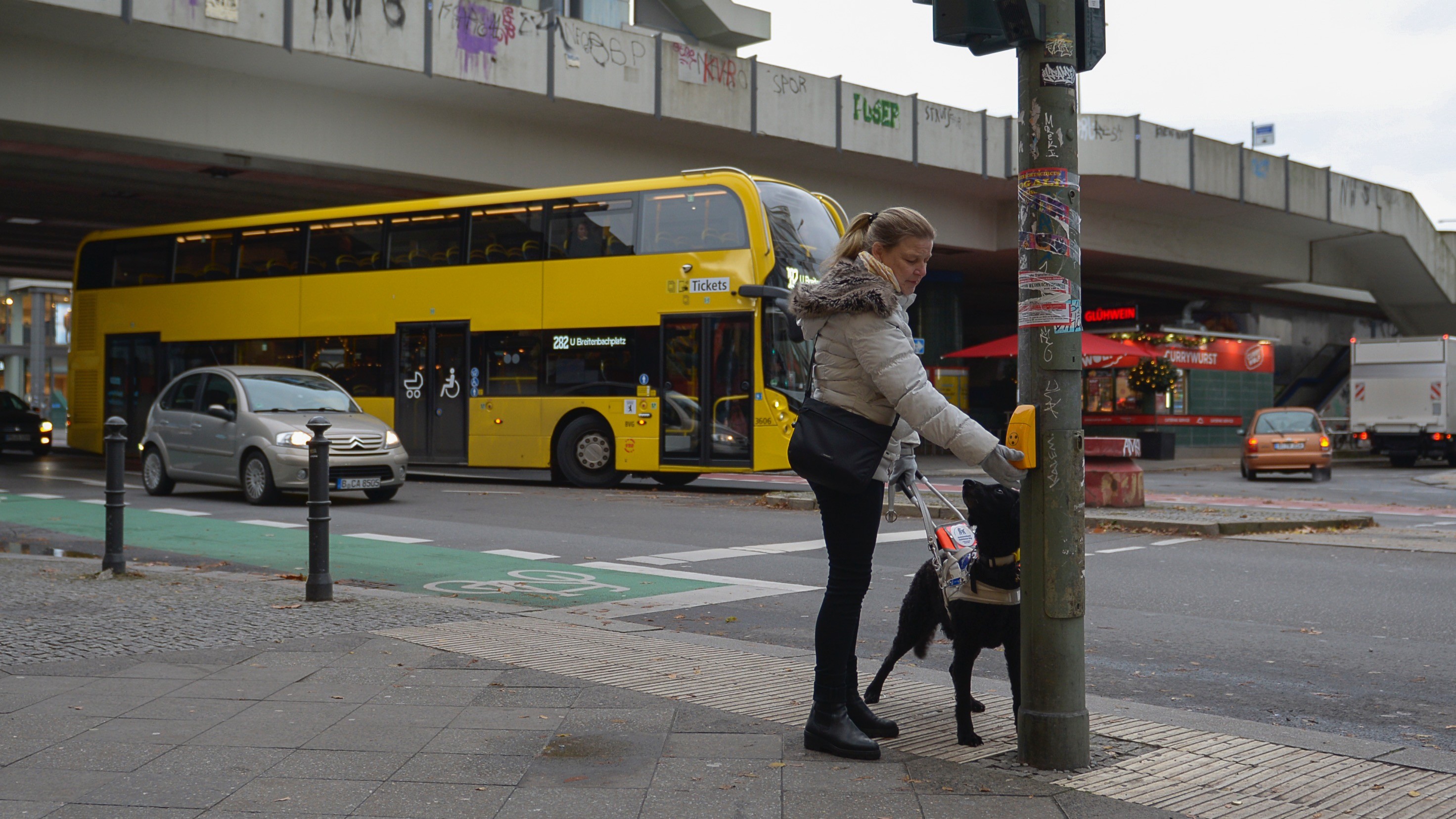 Blindenführhunde Header 16:9 Blinde Frau betätigt Blindensignal einer Ampel für akustische Orientierung.