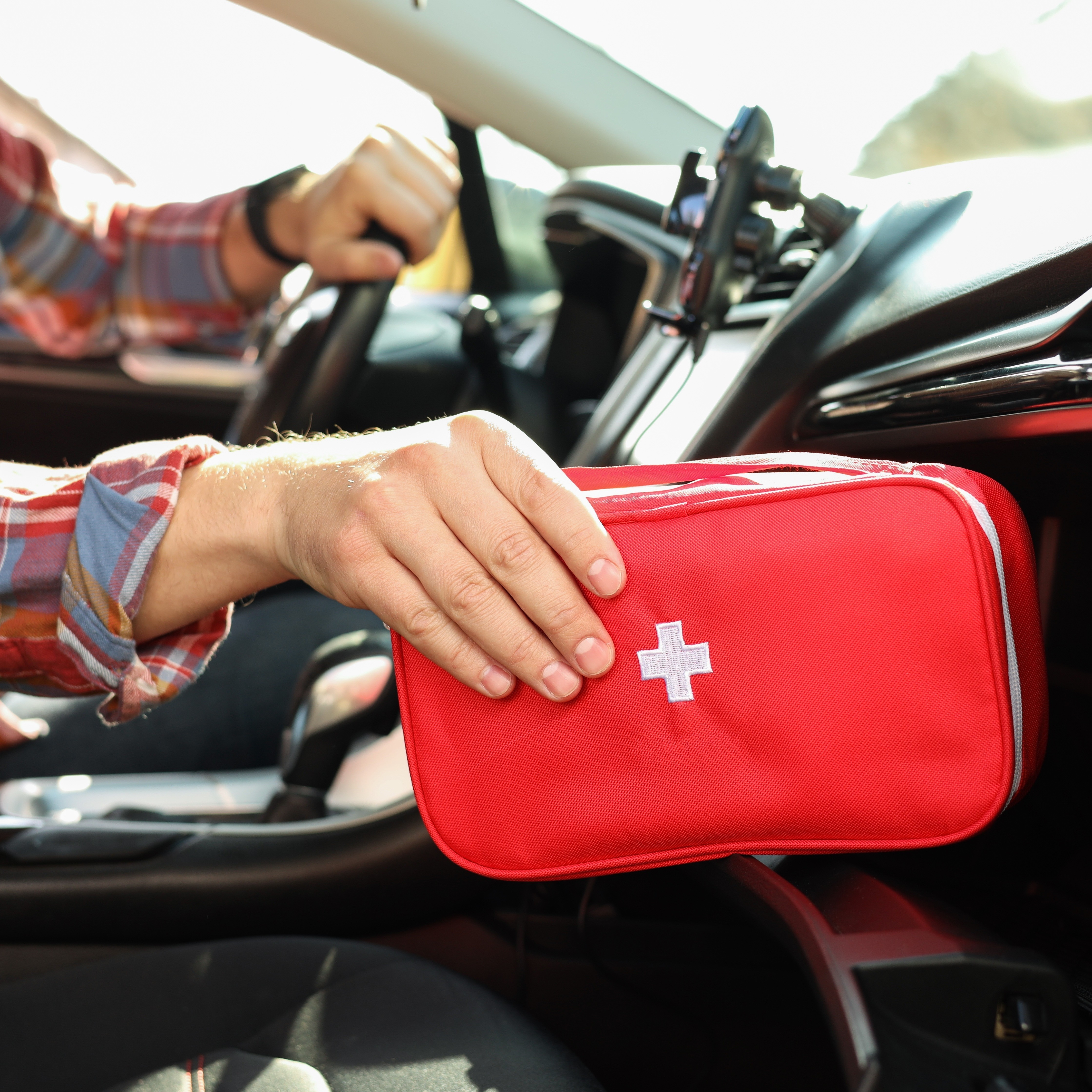 Header mA Erste Hilfe Eine Person nimmt ein Erste-Hilfe-Set aus dem Handschuhfach eines Pkw.