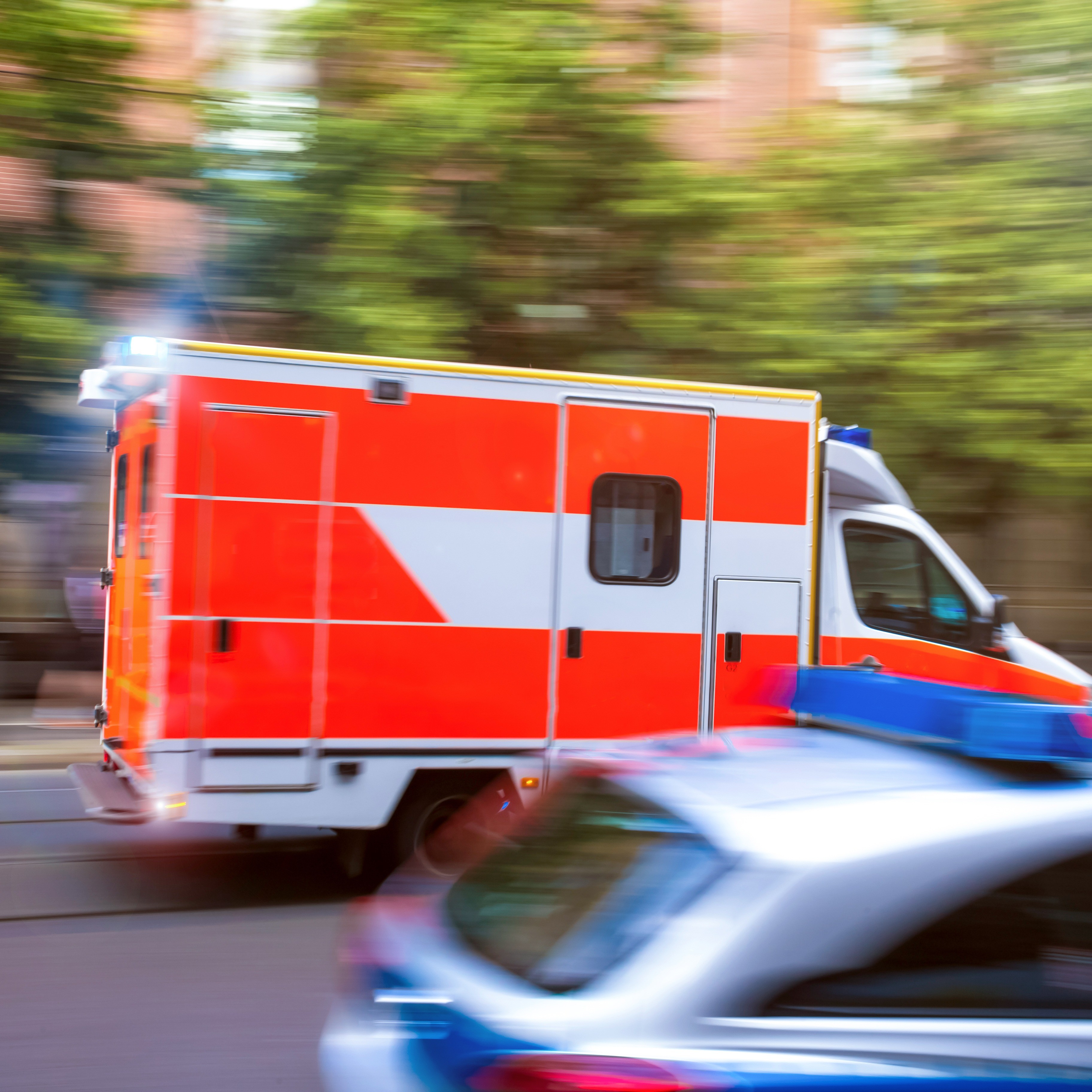 Ein Rettungswagen im Einsatz fährt an einem Polizeiauto und einem Fahrrad vorbei.   