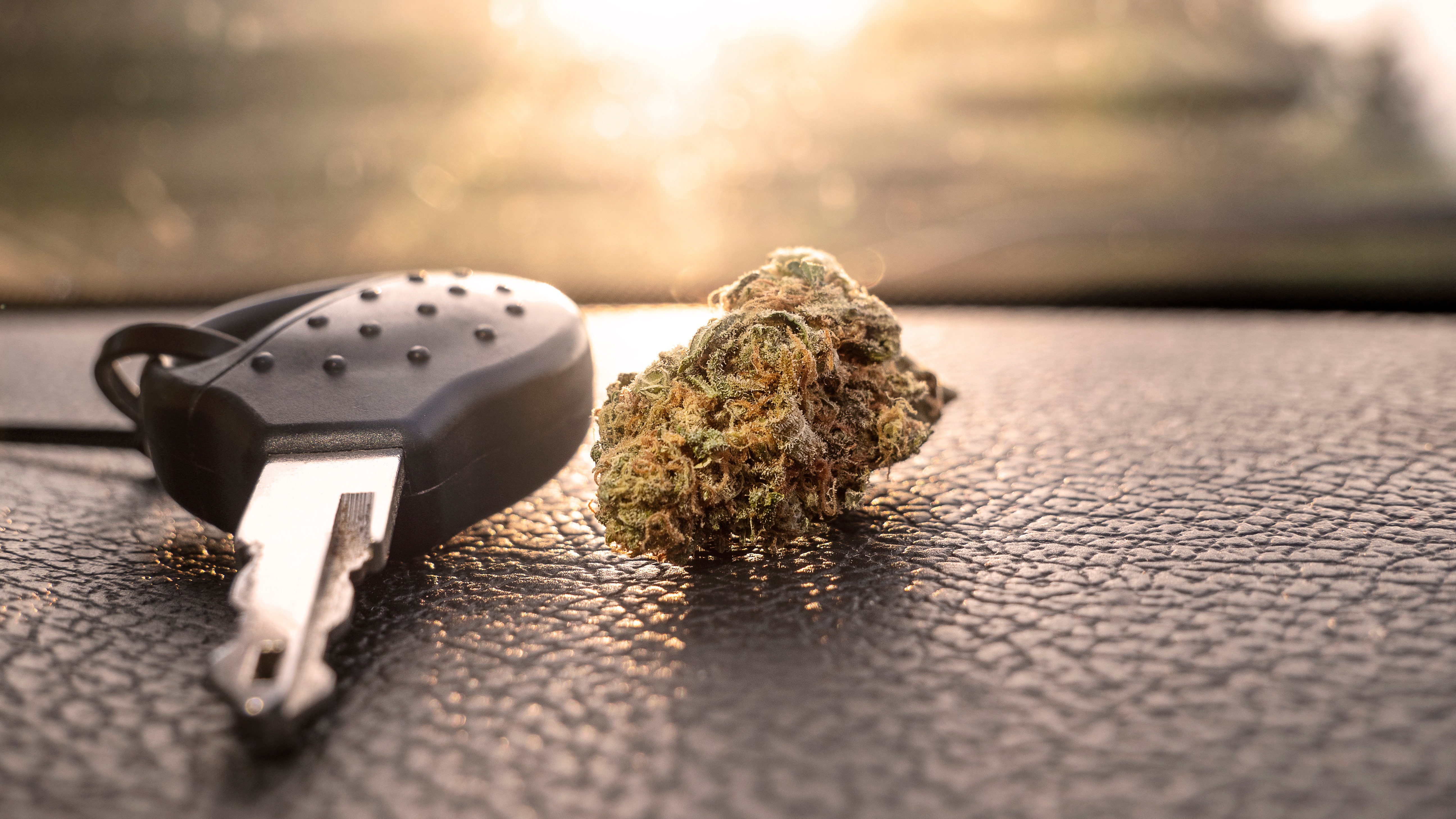 Kiffen oder fahren? Autoschlüssel Cannabis Ein Autoschlüssel und Cannabis auf einem Armaturenbrett.