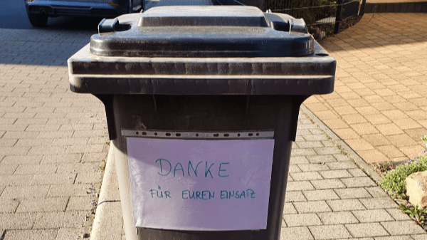 Mülltonne, auf der ein Zettel „Danke für euren Einsatz” klebt.