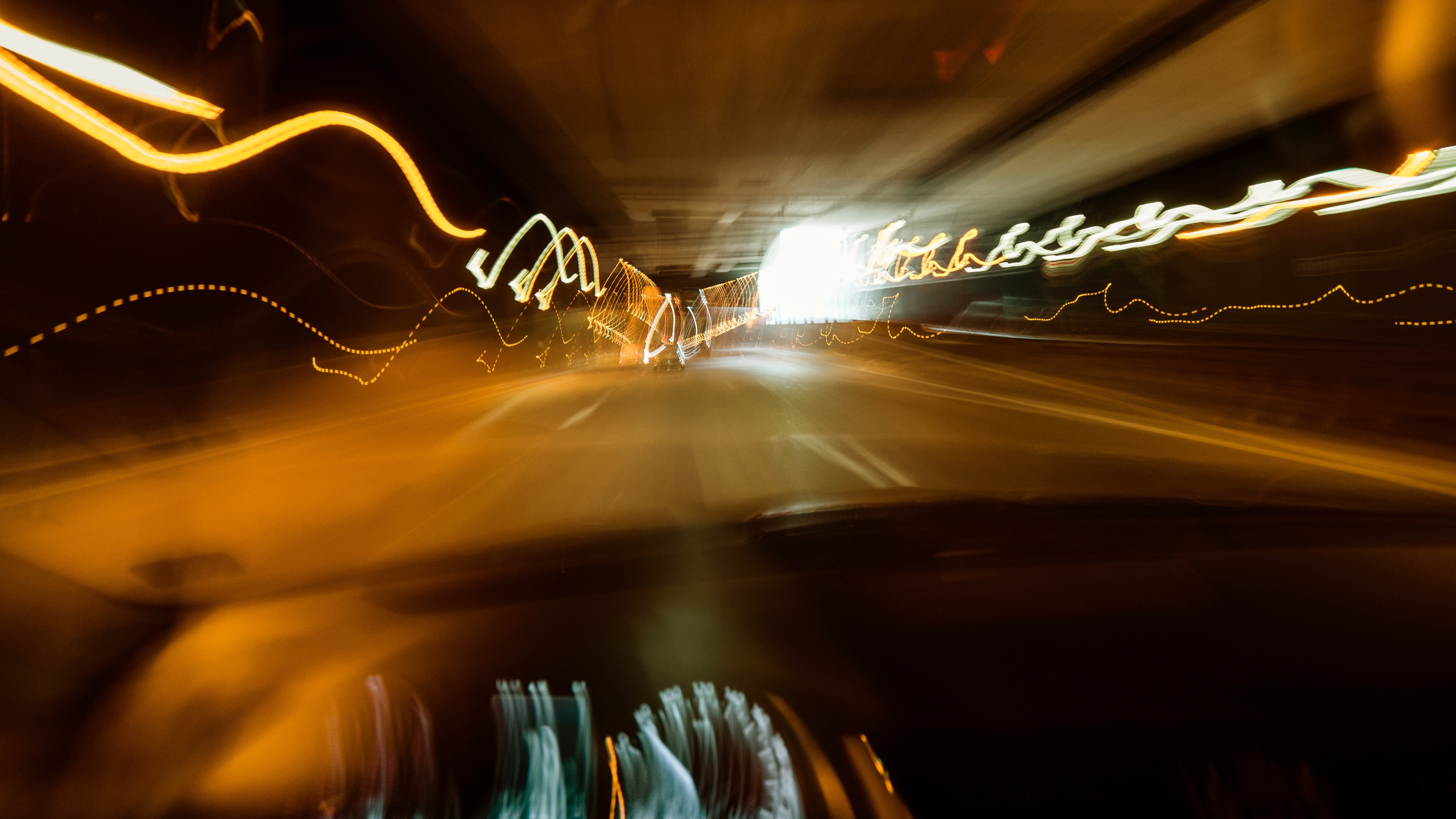 AlkoholVsCannabis Verschwommene Straße Ein verschwommenes Bild in einem Autotunnel. Es sind Lichter und verschiedene Autos zu sehen.